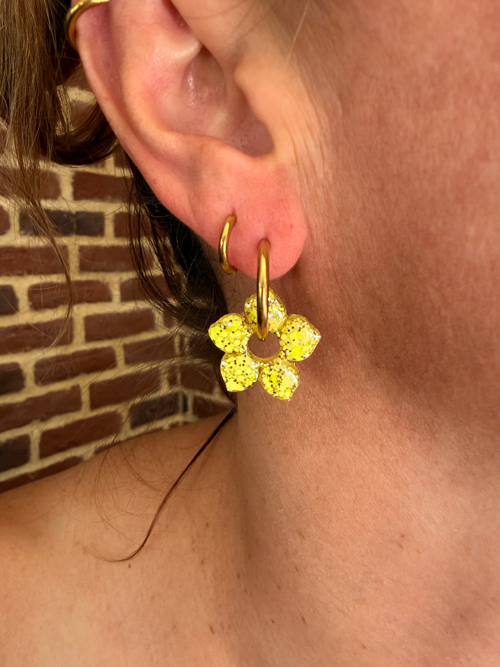 Pampille fleur aux pétales pointus en résine jaune citron portée sur une créole dorée