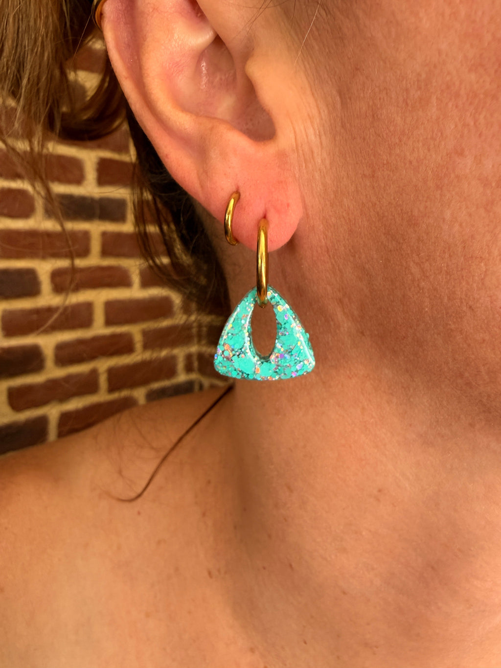 Pampille triangle en résine turquoise portée sur une créole dorée