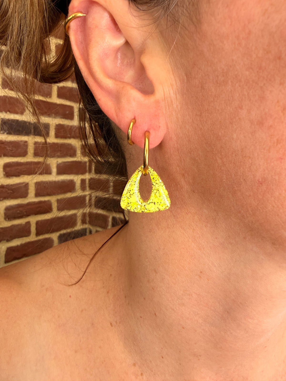 Pampille triangle en résine jaune citron portée sur une créole dorée