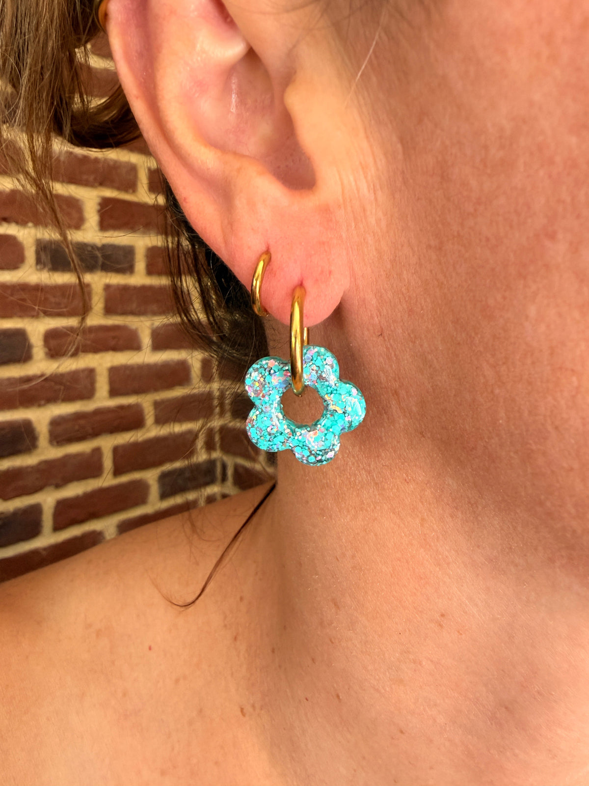Pampille fleur en résine turquoise portée sur une créole dorée