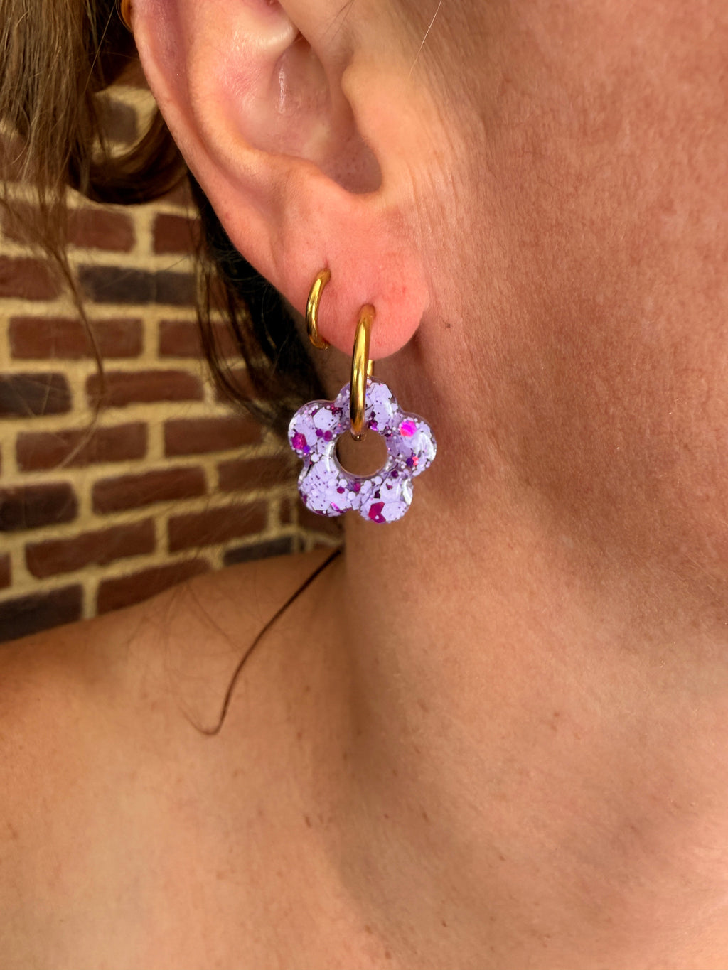 Pampille fleur en résine lilas et fuchsia portée sur une créole dorée