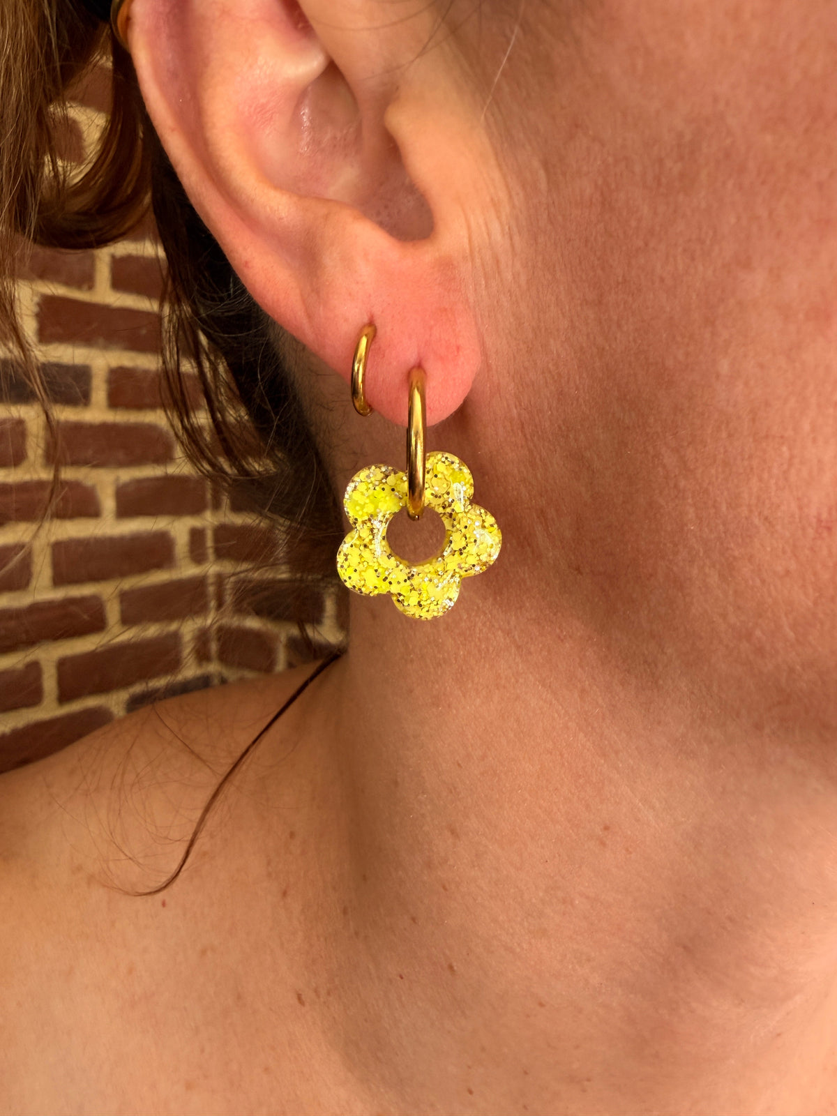 Pampille fleur en résine jaune citron portée sur une créole dorée