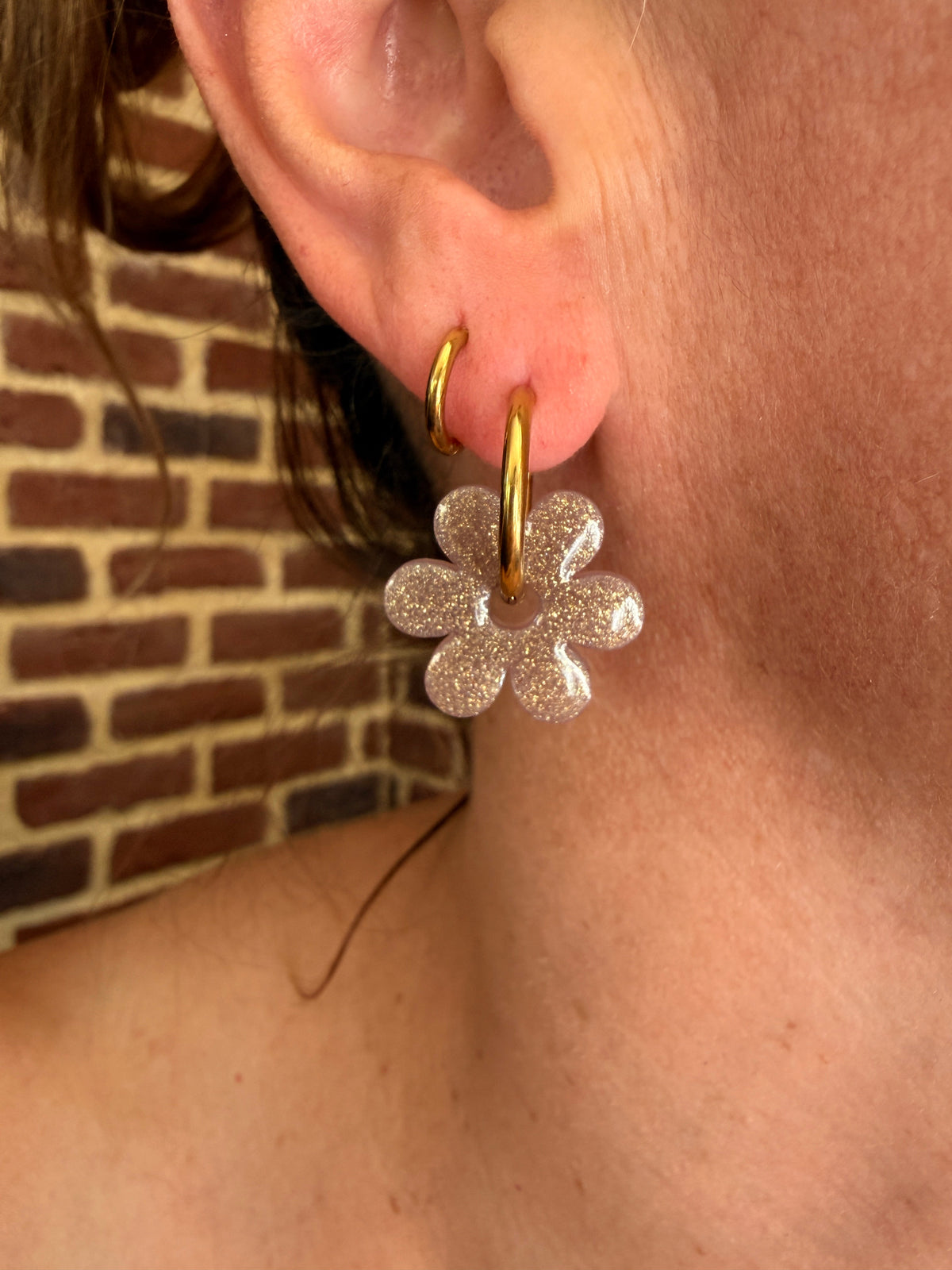 Pampille fleur six pétales en résine argent givré portée sur une créole dorée