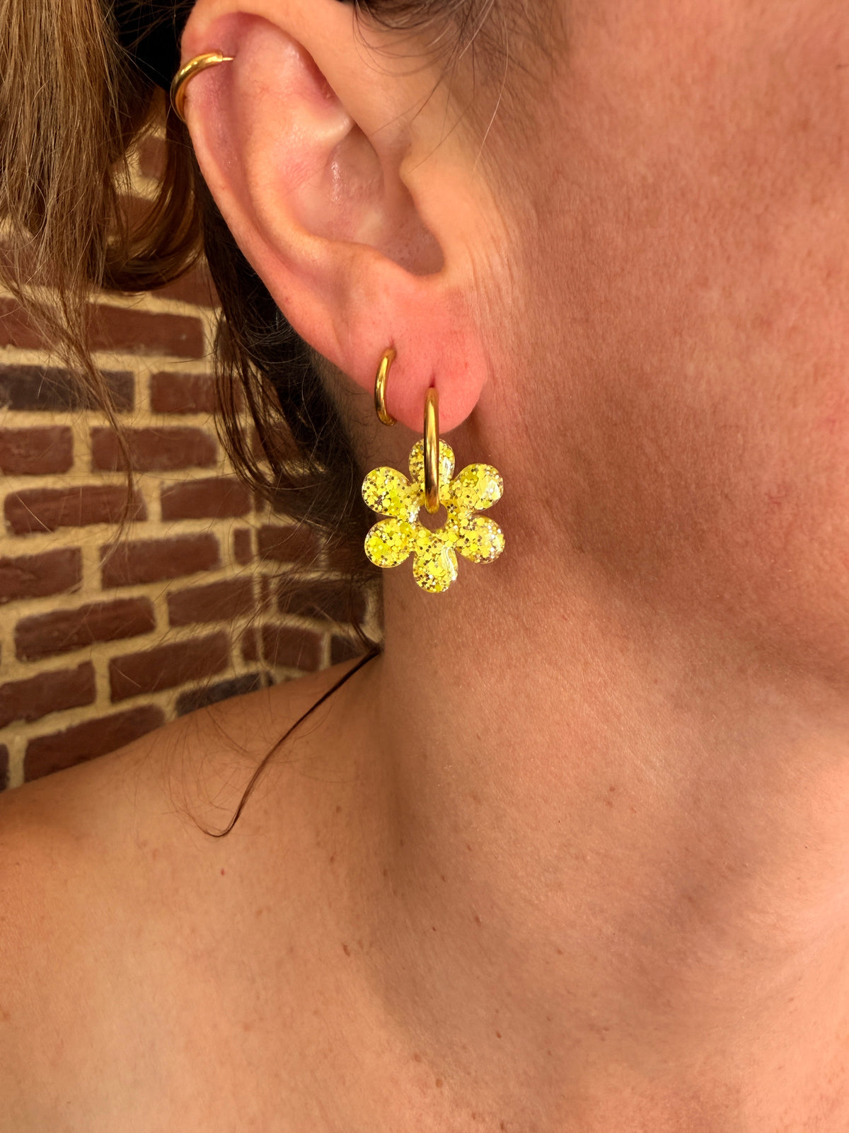 Pampille fleur six pétales en résine jaune citron portée sur une créole dorée