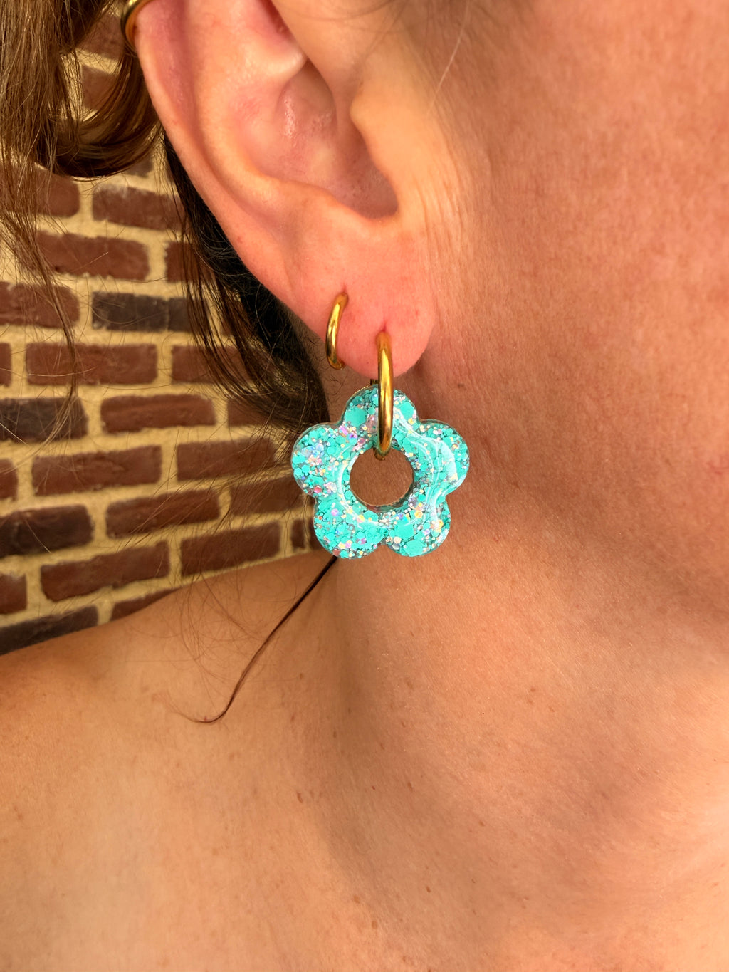 Grande pampille fleur en résine turquoise portée sur une créole dorée