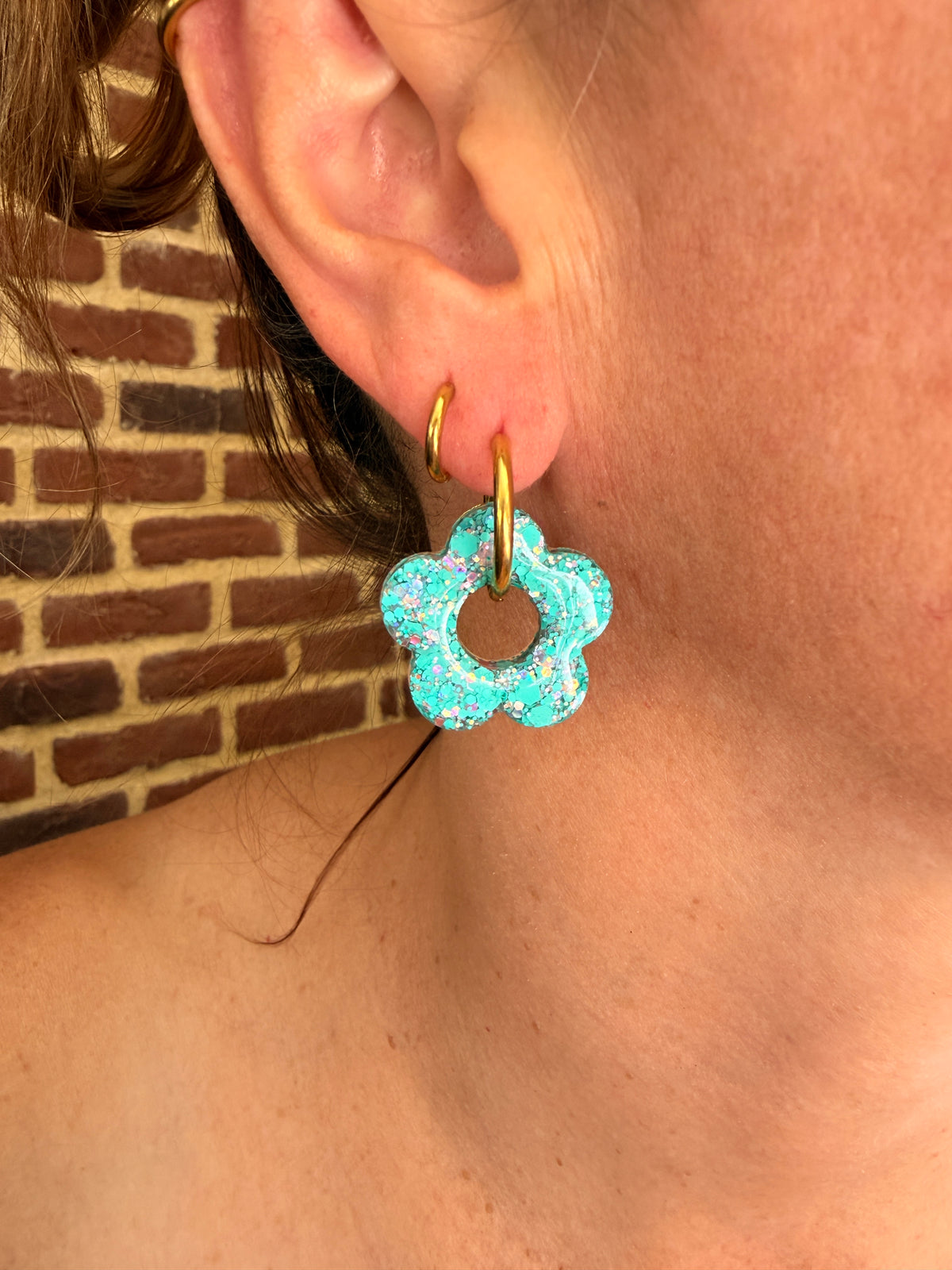 Grande pampille fleur en résine turquoise portée sur une créole dorée